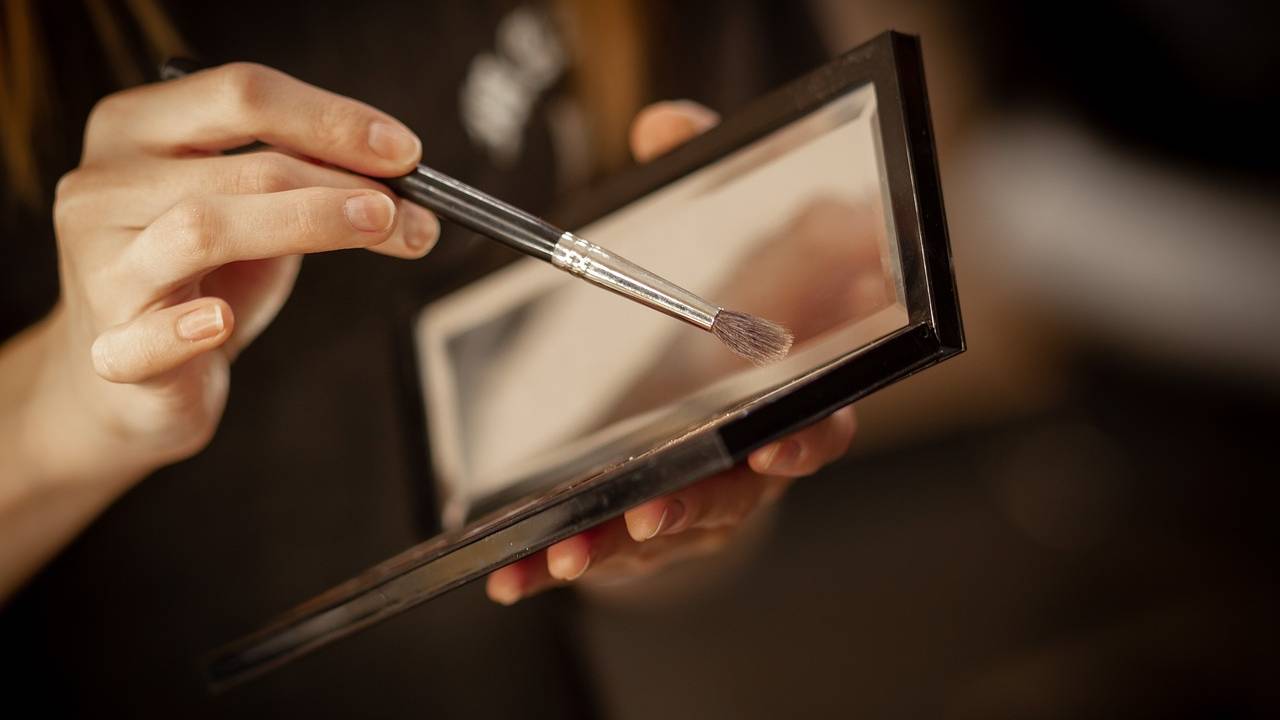 University student brushing makeup